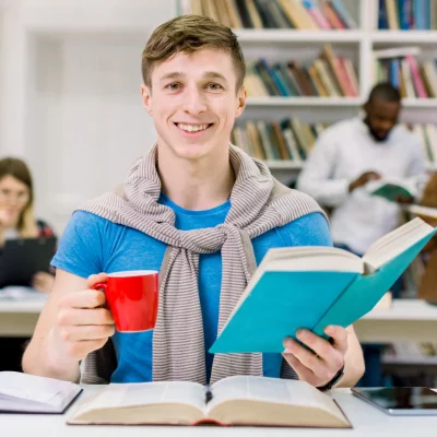 close-up-portrait-joyful-handsome-25-aged-caucasian-man-sitting-table-library-looking-camera-posing-with-book_161094-3345